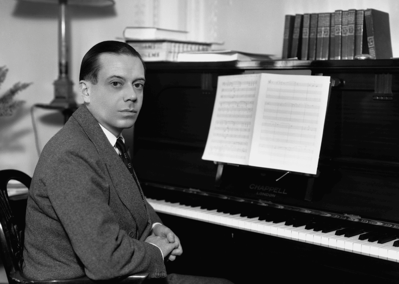 Cole porter sits at piano.